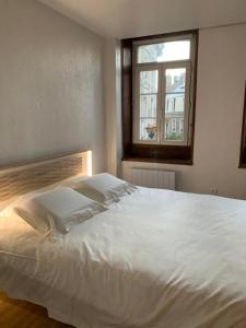 una camera da letto con un grande letto bianco e una finestra di Le cottage des remparts - face hotel de ville a Boulogne-sur-Mer