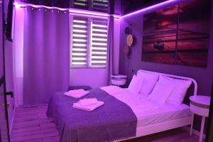 a purple bedroom with a bed with two pink towels on it at Apartament Nadmorski in Ustka
