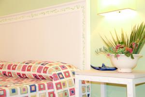 a bedroom with a bed and a table with a potted plant at Hotel O'scià in Lampedusa