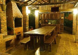 a wooden table and benches in a room with a fireplace at Pousada Arapassu in Eldorado