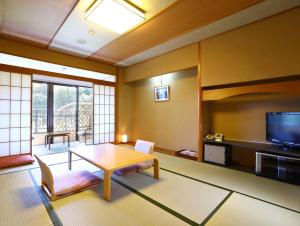 a living room with a table and a tv at Yugawara Chiyodaso in Yugawara