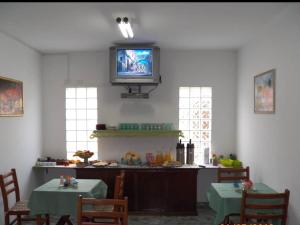 comedor con 2 mesas y TV en la pared en Pousada da Montanha, en Campos do Jordão