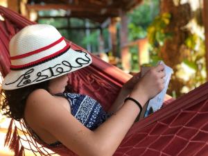 a woman laying in a hammock reading a book at Pousada Arapassu in Eldorado