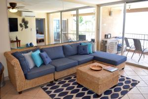 uma sala de estar com um sofá azul e uma mesa em Menehune Shores 309 em Kihei