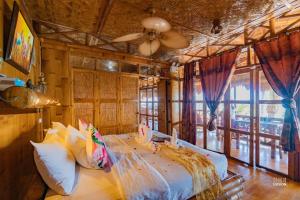 Schlafzimmer mit einem Bett und einem Deckenventilator in der Unterkunft The Coral Blue Oriental Beach Villas and Suites in Bantayan