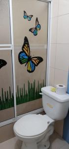 a bathroom with a toilet and butterflies on the wall at Hotel Internacional en Atacames in Atacames