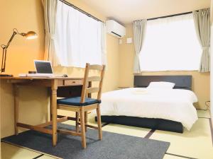 een slaapkamer met een bureau, een bed en een laptop bij NAGAHORI HAIRU DOTONBORI CONDO in Osaka