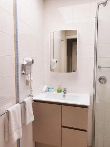 a bathroom with a shower, sink, and mirror at Korora Bay Village Resort in Coffs Harbour