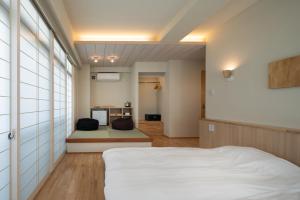 a bedroom with a white bed and a kitchen at Arima Koyado Uraku in Kobe