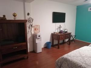 1 dormitorio con 1 cama, TV y nevera en Lepa Mukawa ( Descansa Bonito), en San Juan Teotihuacán