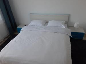 een groot wit bed met witte lakens en kussens bij DORIN COLINA MAREI in Sinaia