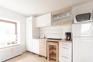eine Küche mit weißen Schränken und einem weißen Kühlschrank in der Unterkunft Ferienwohnung an der Ostsee in Elmenhorst