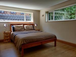a bedroom with a large bed and two windows at Whitehouse Cottage - Great Paxton in Saint Neots