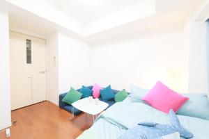 a living room with a blue couch with colorful pillows at IBASHO ShibuyaDogenzaka810 in Tokyo