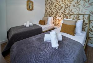 two beds in a hotel room with towels on them at El Coso Boutique Lucena in Lucena