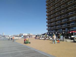 a group of people walking on a boardwalk on the beach at Residentie Aldis met zeezicht in Ostend