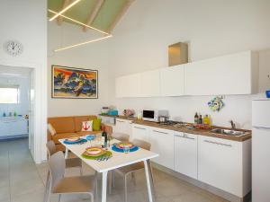a kitchen with white cabinets and a table with chairs at Portofelice Camping Village in Eraclea Mare