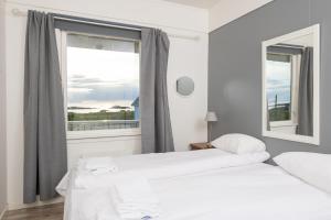 two beds in a room with a window at Apt 103 - Andenes Whale Safari Apartments in Andenes