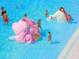 a group of people in a pool with inflatable animals in the water at Portofelice Camping Village in Eraclea Mare