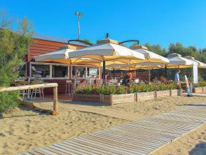 a restaurant with tables and umbrellas on the beach at Portofelice Camping Village in Eraclea Mare