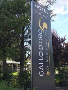 a sign for a hotel with trees in the background at Hotel Ristorante Gallo D'Oro in Vignola