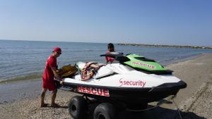 two men are pulling a boat on the beach at Portofelice Camping Village in Eraclea Mare