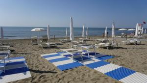 a beach with blue and white chairs and umbrellas at Portofelice Camping Village in Eraclea Mare