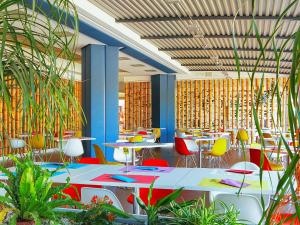 a restaurant with tables and colorful chairs and plants at Portofelice Camping Village in Eraclea Mare