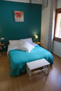 a bedroom with a blue bed with a bench next to it at Hotel Arbre De Neu in Encamp