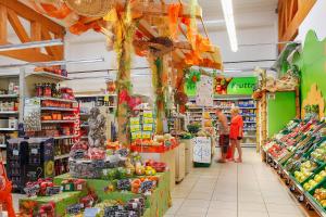 a grocery store aisle with people standing in the produce section at Portofelice Camping Village in Eraclea Mare