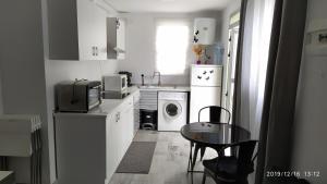 a small white kitchen with a table and a washing machine at Apartamento Calarreona in Águilas