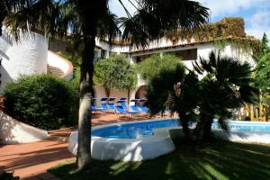 una piscina con sillas y palmeras junto a un edificio en Hotel Villa Mediterranea, en Marina di Noto