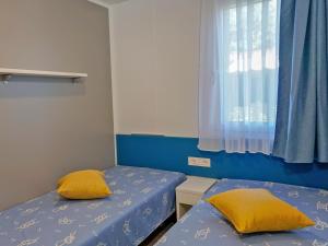two beds with yellow pillows in a room with a window at Portofelice Camping Village in Eraclea Mare