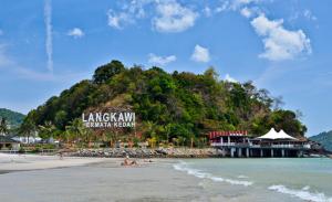 a resort on a beach with people on the beach at Zeala Asmara Motel in Kuah