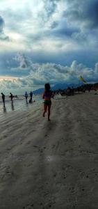 瓜埠的住宿－扎拉阿斯馬拉汽車旅館，一名妇女带着风筝在海滩上跑