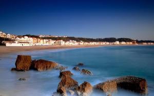 a view of a beach with rocks in the water at Apartamentos Mare in Nazaré
