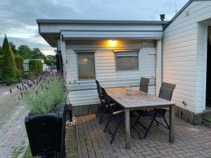 a patio with a wooden table and chairs in front of a house at Beach House Giethoorn in Wanneperveen