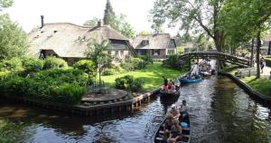 a group of people riding in gondolas down a river at Beach House Giethoorn in Wanneperveen