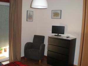 a living room with a chair and a television at Casa do Linhar - Quintas de Sirlyn in Tondela