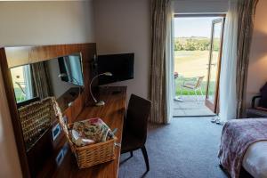 Habitación de hotel con escritorio con espejo y dormitorio en Lanhydrock Hotel & Golf Club, en Bodmin