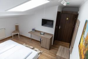 a bedroom with a bed and a desk and a tv at Pensiunea Sofia in Satu Mare