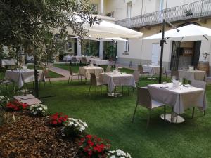 un restaurante con mesas y sillas blancas y sombrillas blancas en Locanda La Francisca, en Omegna