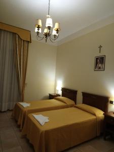 Habitación de hotel con 2 camas y lámpara de araña. en casapaceebene, en San Giovanni Rotondo