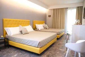J Luxury Home في تروبيا: سريرين في غرفة الفندق مع أسرة صفراء