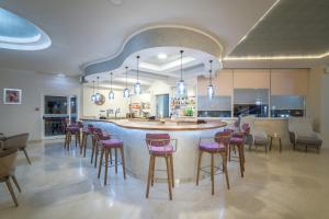 a large kitchen with a bar with pink stools at Golden Sun Hotel in Kalamaki