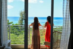 恩納村にあるオディシス恩納リゾートホテルの海を望むバルコニーに立つ女性2名