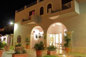 um edifício com vasos de plantas num pátio à noite em Hotel O'scià em Lampedusa