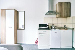 a kitchen with white cabinets and a microwave at Pension & Monteurwohnungen Burglesum Bremen in Bremen