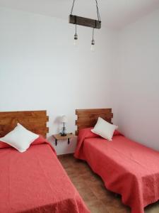 two beds in a room with red sheets at Casa Celia - Casitas las Abuelas - vida rural in Breña Alta