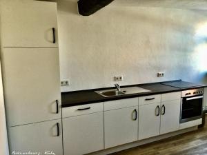 uma cozinha com armários brancos e um lavatório em Dr. Fabian und Christine Drube em Immenhausen